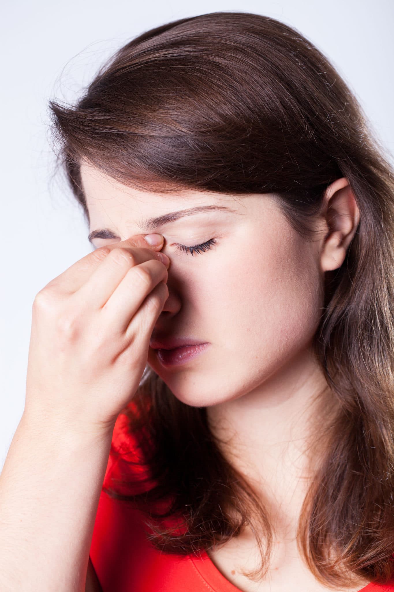 ENT-Nosebleed Woman pinching the bridge of her nose and looking distressed